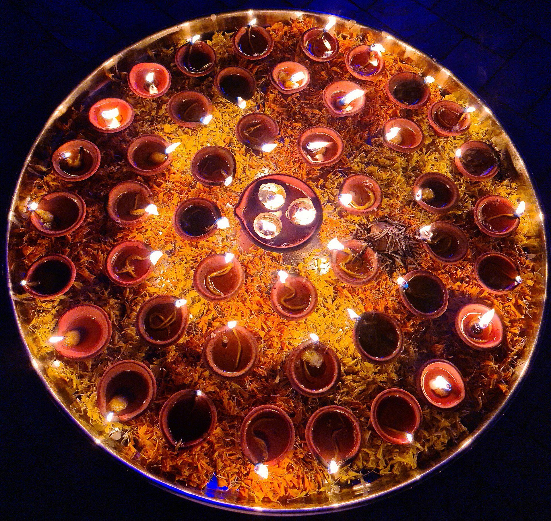 A ceremonial thali illuminated with rows of diyas